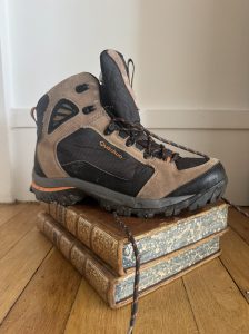 Une chaussure de randonnée posée sur un livre ancien relié