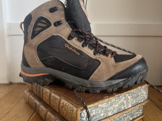 Une chaussure de randonnée posée sur un livre ancien relié