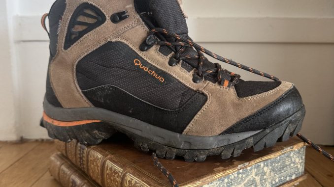 Une chaussure de randonnée posée sur un livre ancien relié
