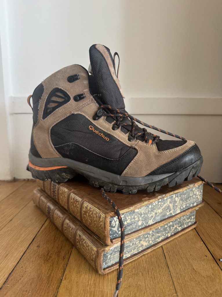 Une chaussure de randonnée posée sur un livre ancien relié