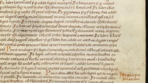 Page de manuscrit latin du début du XIIe siècle, écriture caroline sur une colonne, rubriques rouges en marge : le chapitre des signes de la main pour demander les livres au scriptorium.